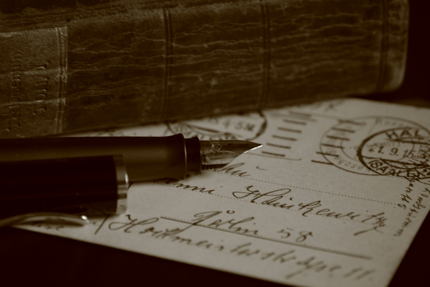 A vintage fountain pen rests on a handwritten postcard.